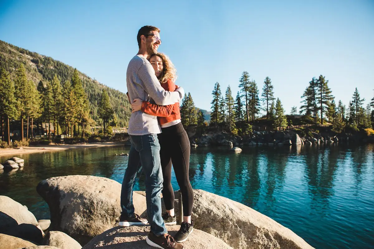 Couple hugging on rocks enjoying Sand Harbor overlooking Lake Tahoe